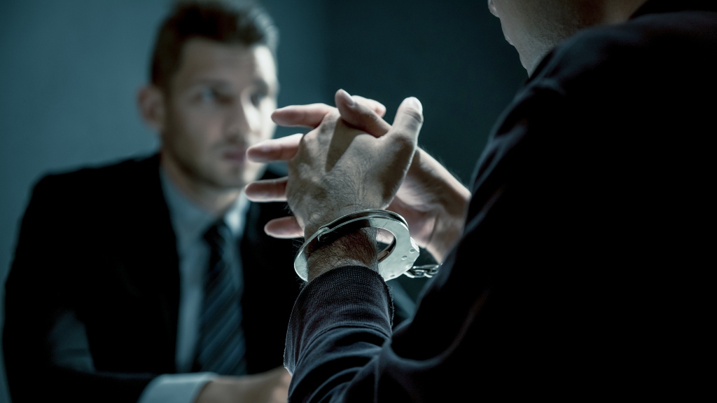 a man in handcuffs talks to a lawyer