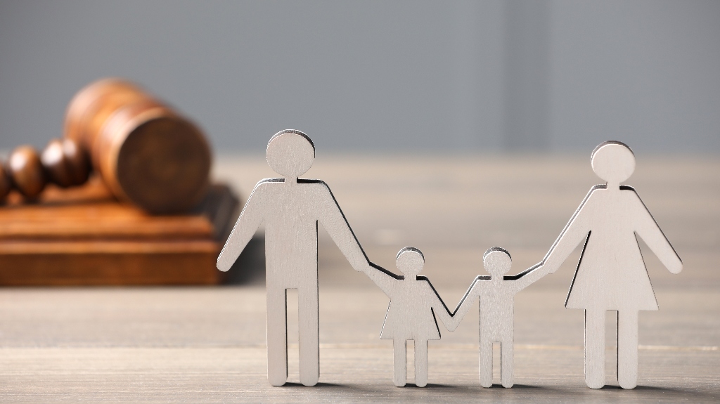 Figure of parents with children and gavel on wooden table