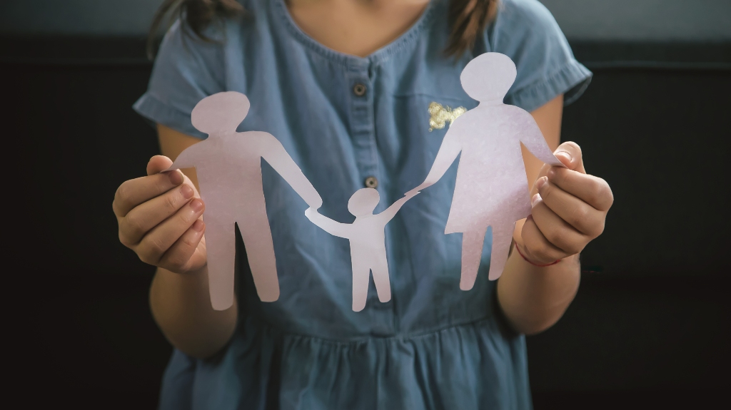 Little girl is holding family figures from paper