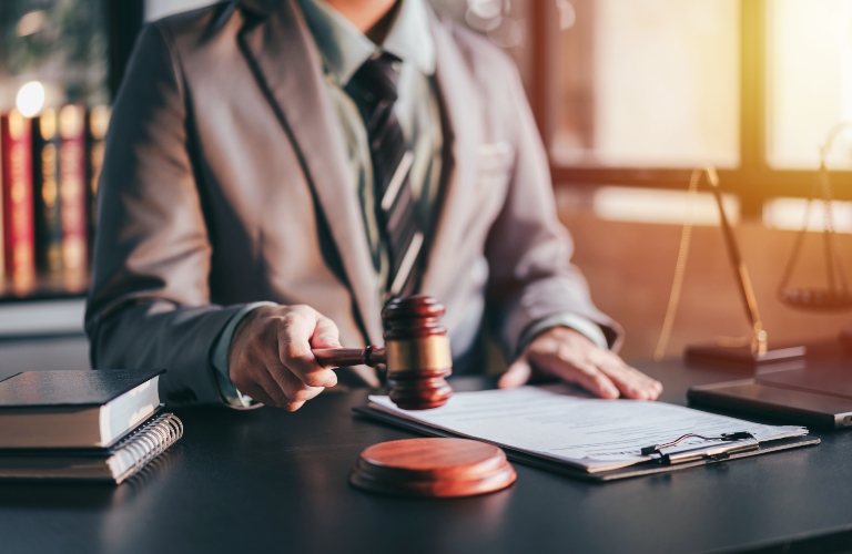 Adult Asian man in suit holding a gavel in a law office